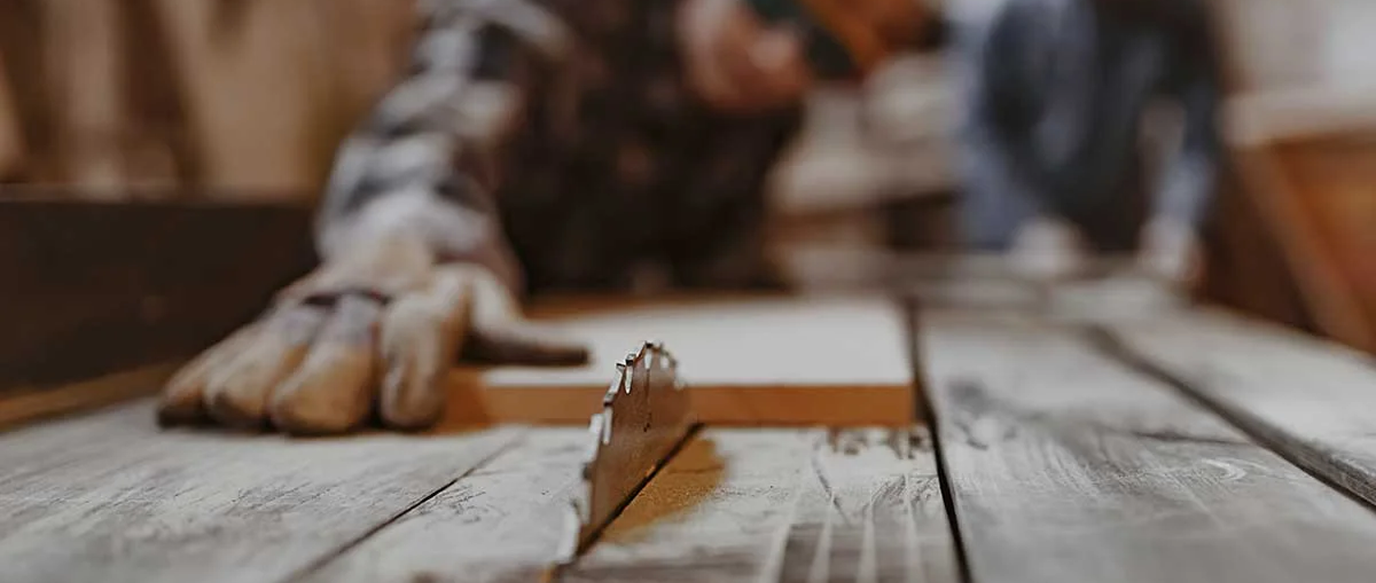 Blurred background image of a woodworker using a table saw cutting wood, with overlay text reading “Industry Spotlight: Woodwork, Millwork & Cabinetry” and a “Shop Now” button.